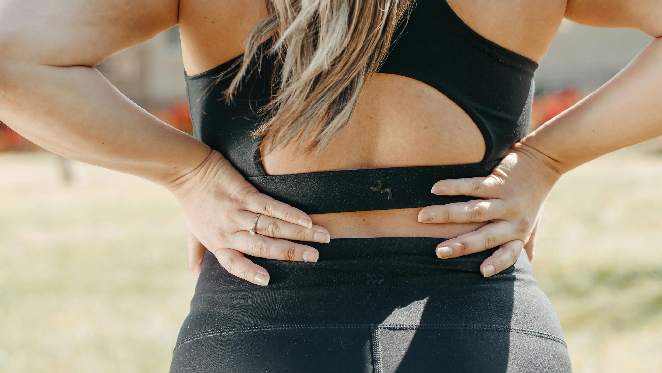 Woman holding lower back in pain showing symptoms of low back pain in Queen Creek AZ