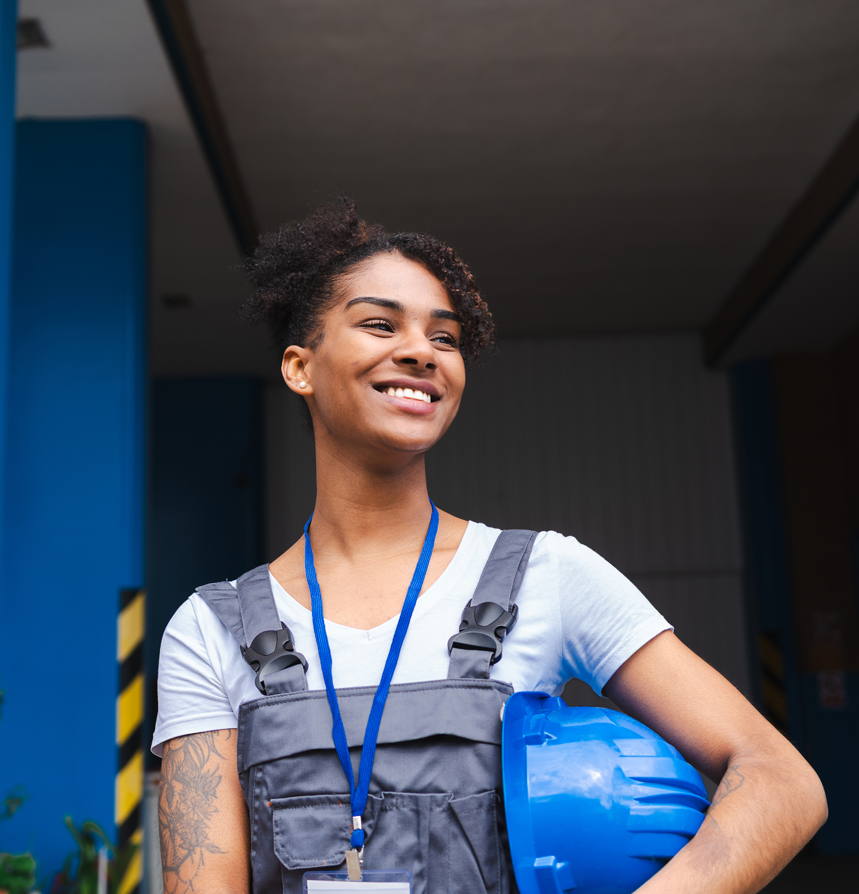 Woman in construction workwear holding a hard hat, representing physically demanding jobs that may contribute to low back pain.