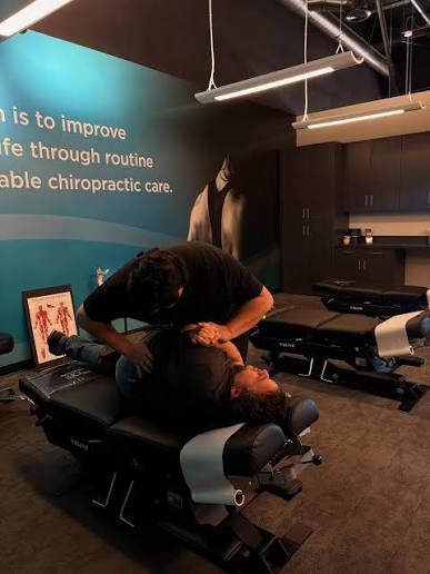The Joint Chiropractor performs a side-posture manual adjustment on a patient lying on a specialized treatment table to realign the pelvis, lumbar spine, and sacroiliac joint for hip pain relief.